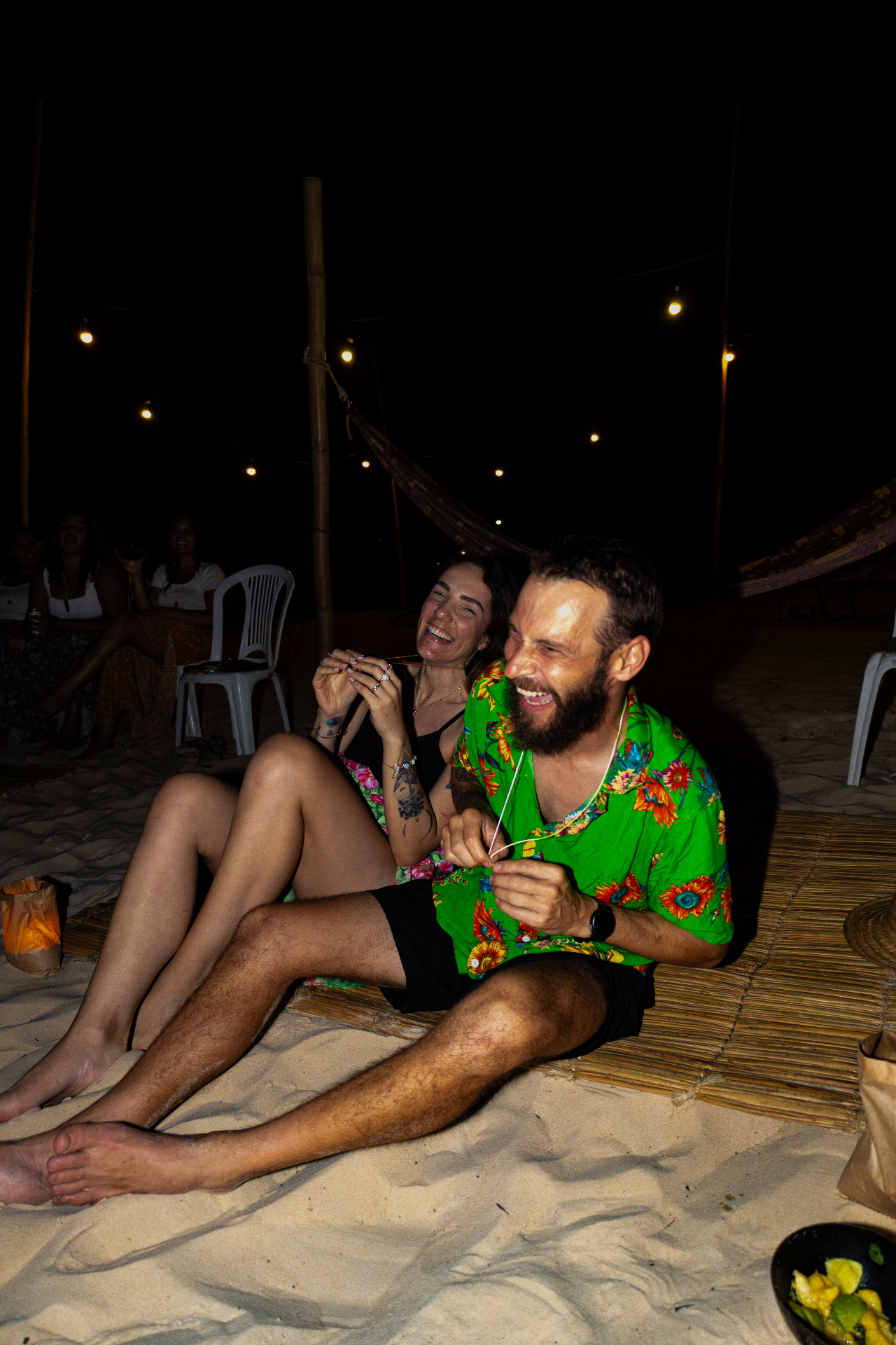 casal rindo na praia à noite